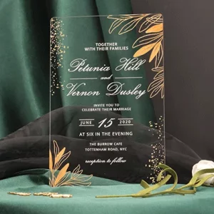 Crystal clear acrylic wedding invitation HPA289 with gold metallic text and leaf print sitting inside a transparent envelope